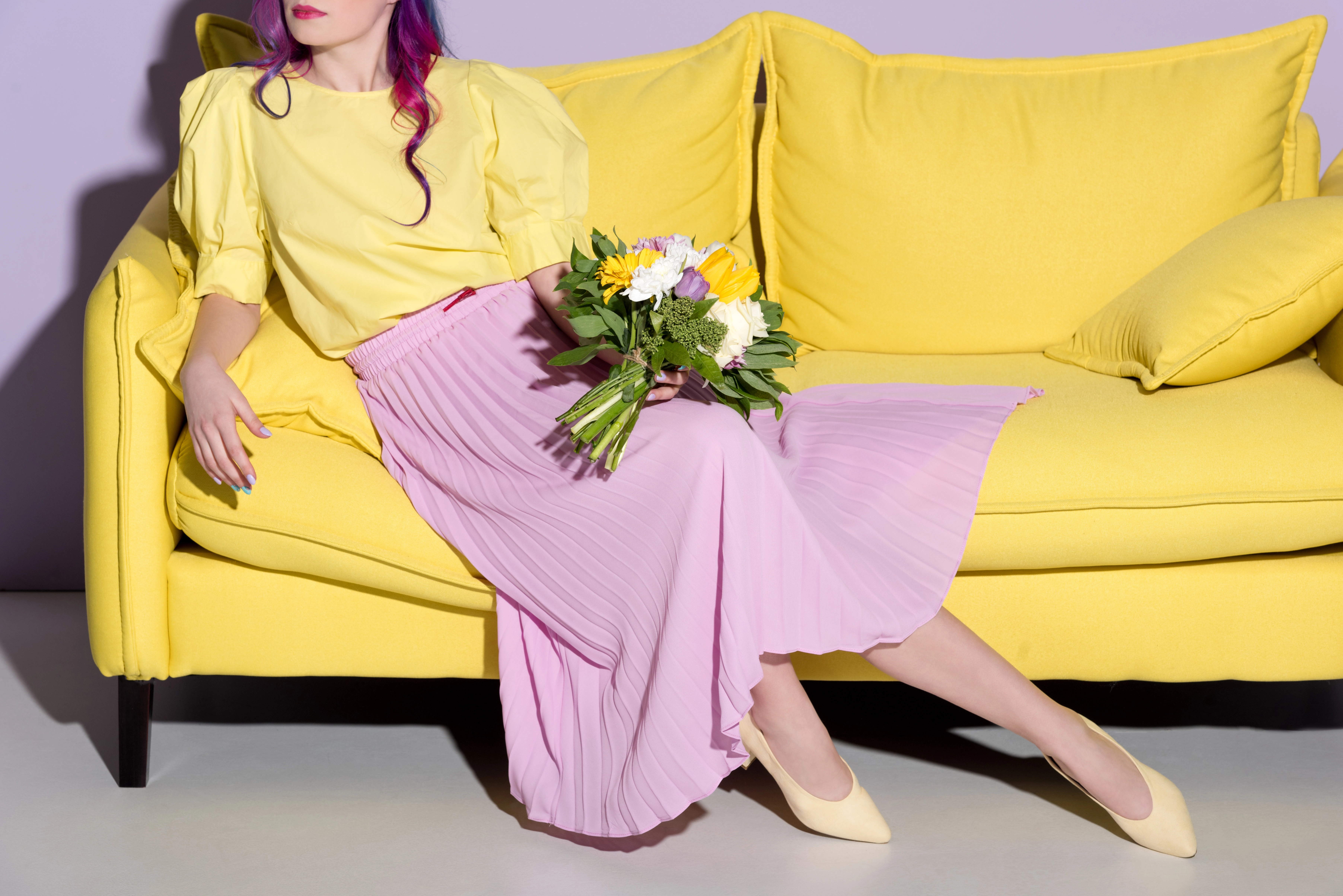 girl sitting on yellow couch holding a bouquet of flowers