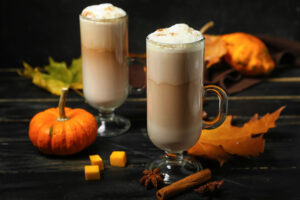 two coffee drinks with a small pumpkin